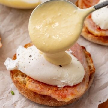 Spooning the hollandaise sauce on top of the poached eggs.