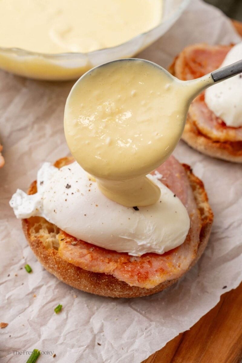 Spooning the hollandaise sauce on top of the poached eggs.