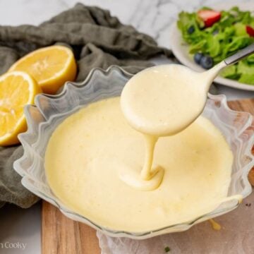 Hollandaise sauce in a bowl with a spoon picking some up.