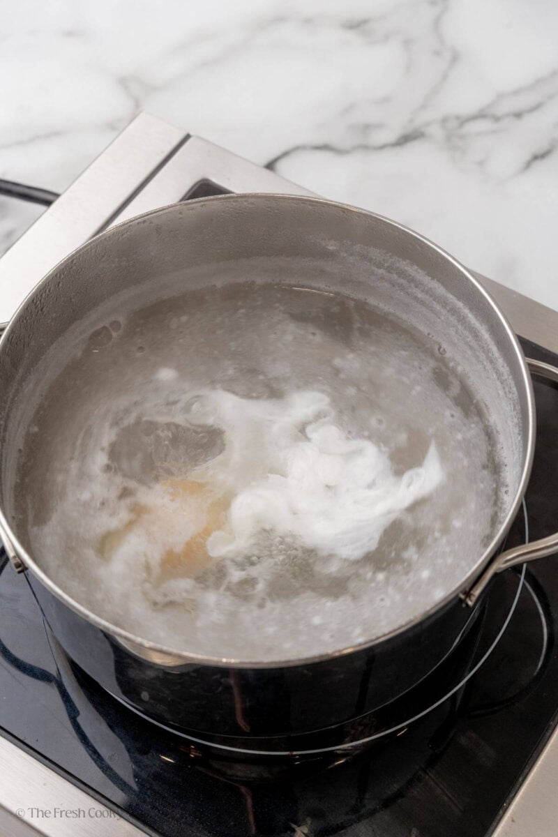 Egg in the boiling water being poached.