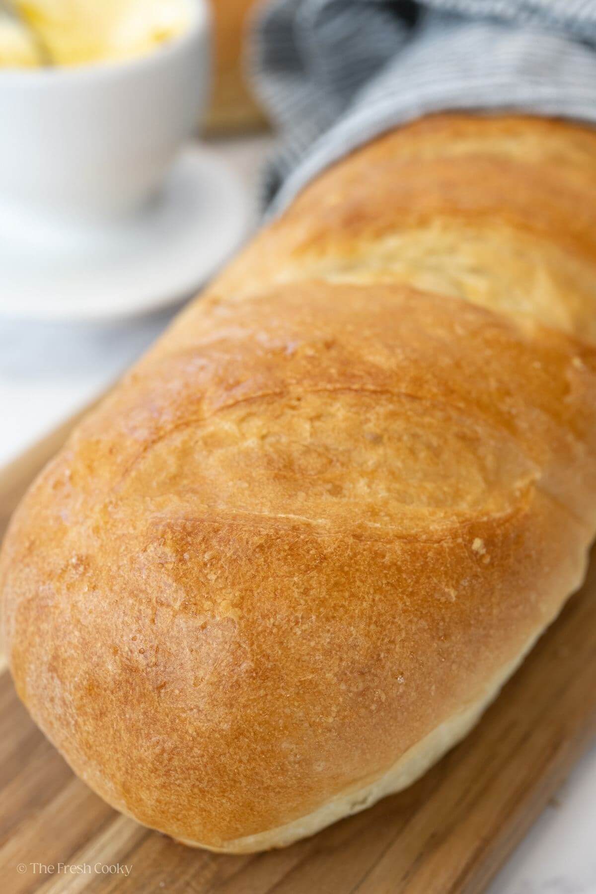 Close up of a loaf of French bread on a wooden board.