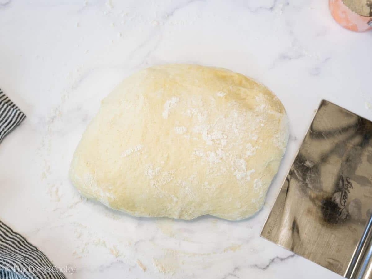 Bread dough turned out onto a floured surface to be shaped.