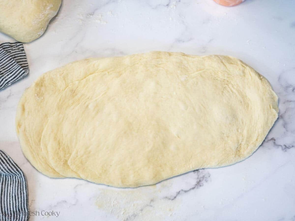 Bread dough rolled out into a flat oval.