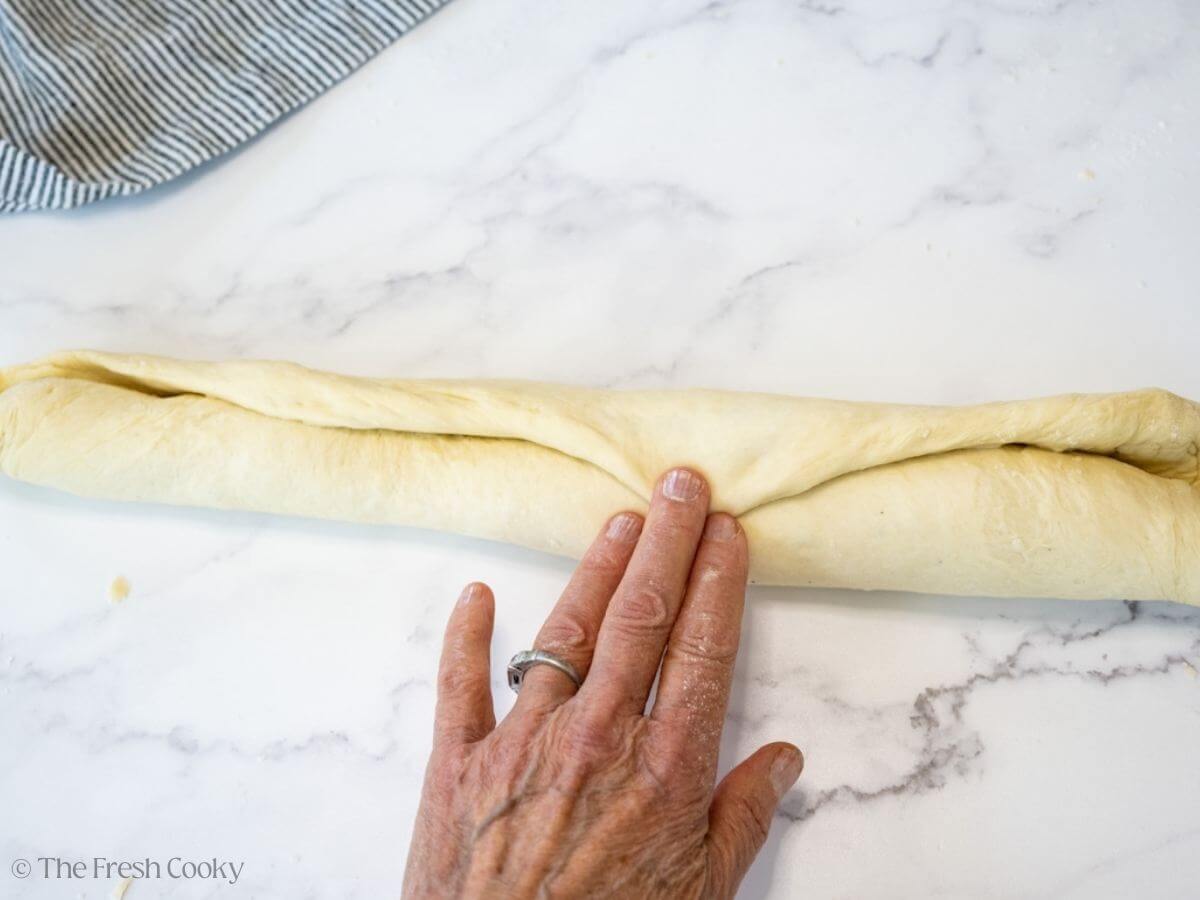 Hand rolling the dough into a log and pressing the ends of the dough together.
