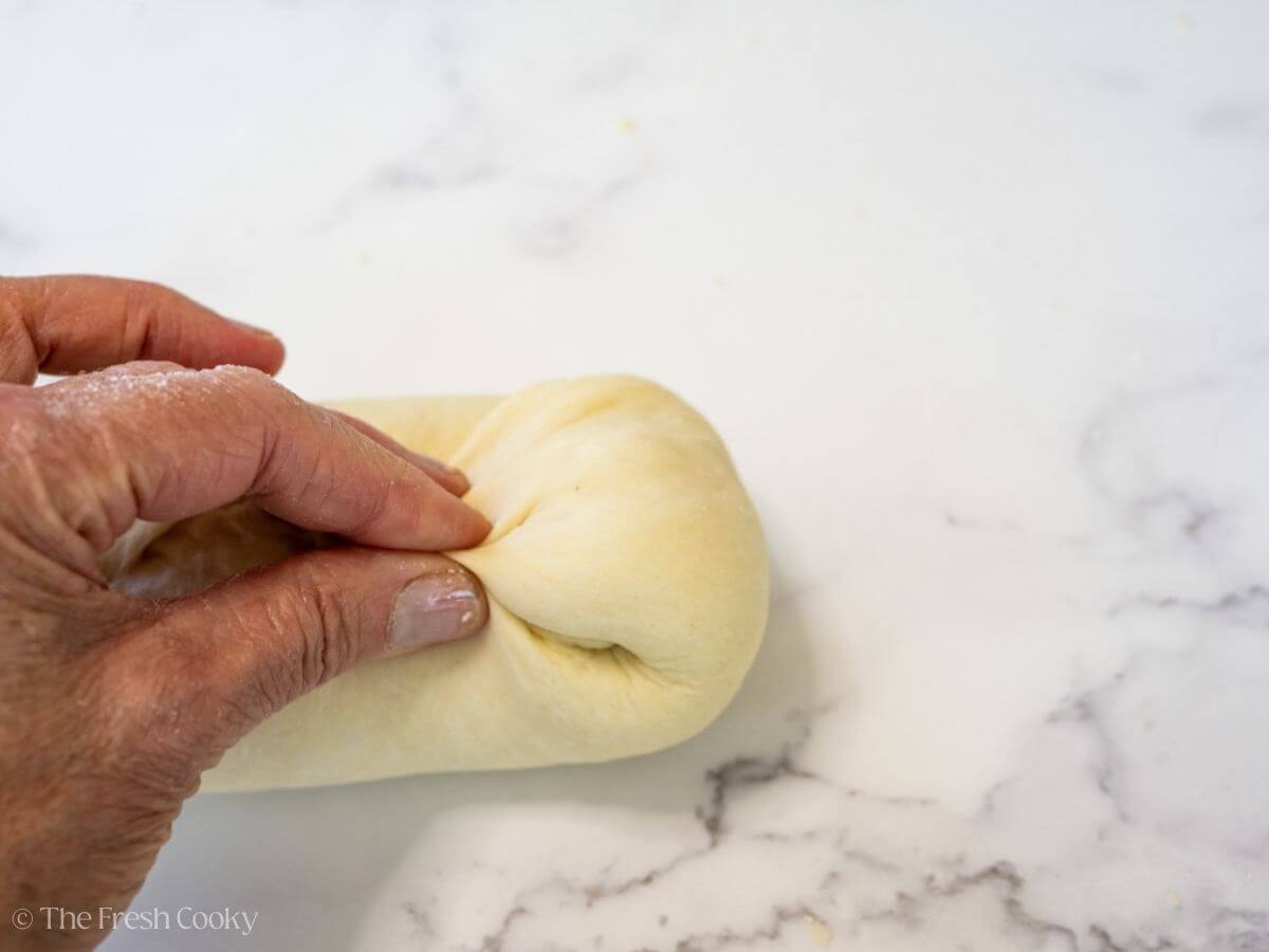 Fingertip pressing the ends of the dough together.