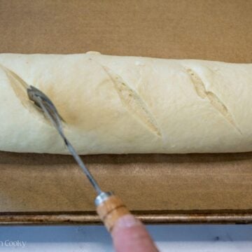 Using a bread razor to cut the dough on the top.