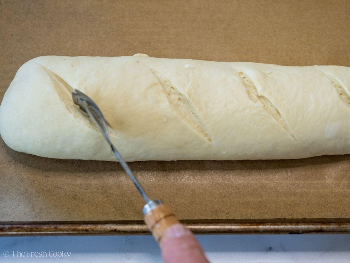 Using a bread razor to cut the dough on the top.