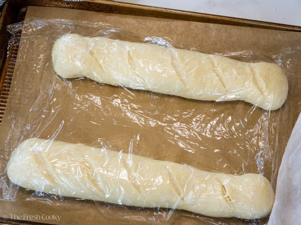 Piece of plastic wrap on top of French bread loaves while rising.