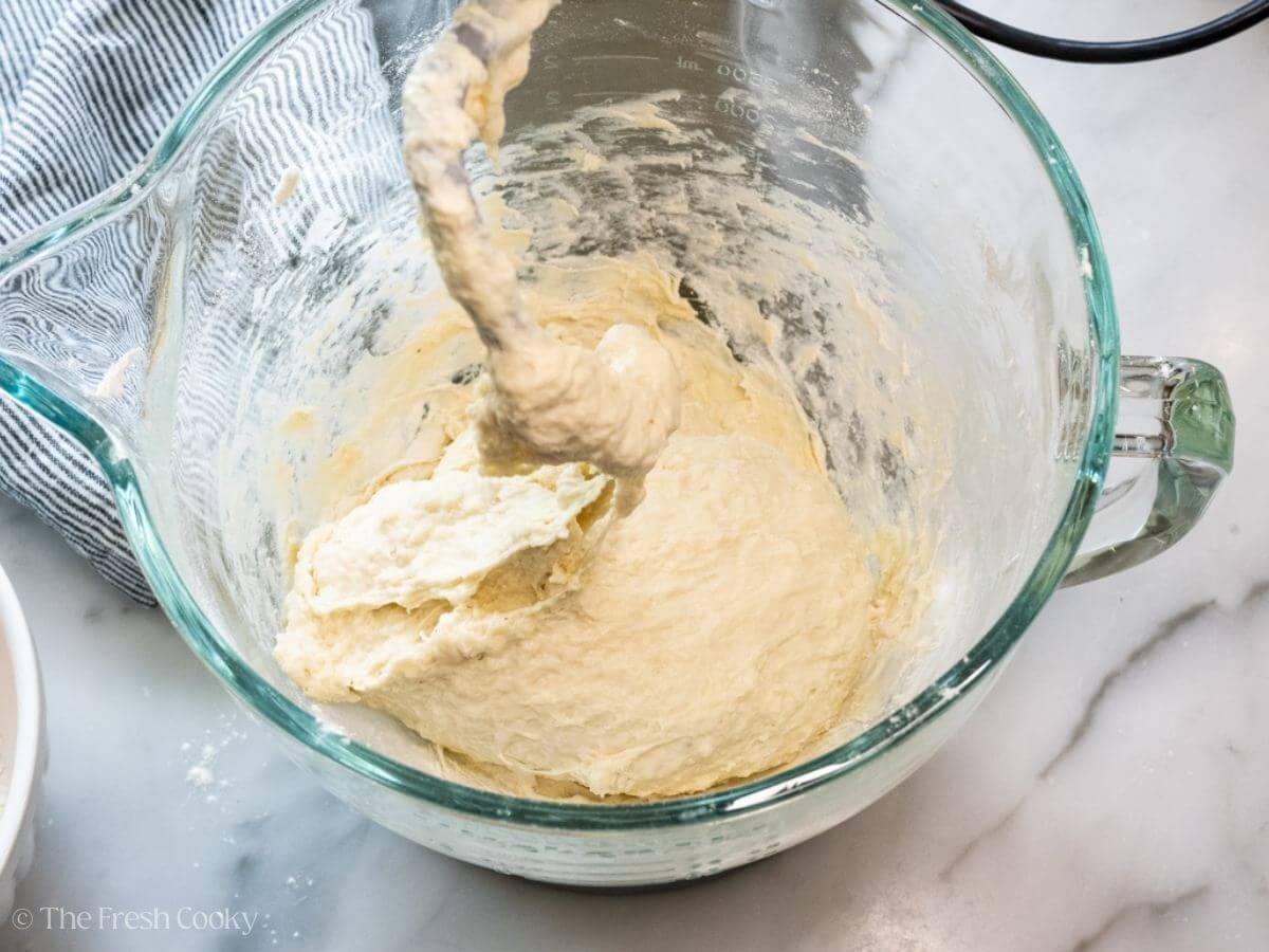 Bread dough in a stand mixer bowl with the dough hook.