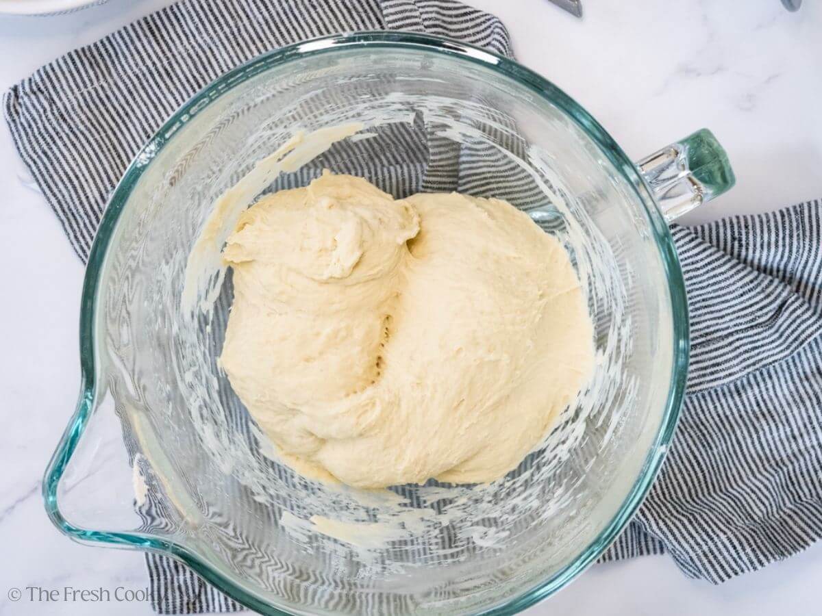 Bread dough in a stand mixer bowl before kneading.