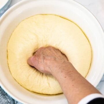 Punching the risen dough down in a large bowl.