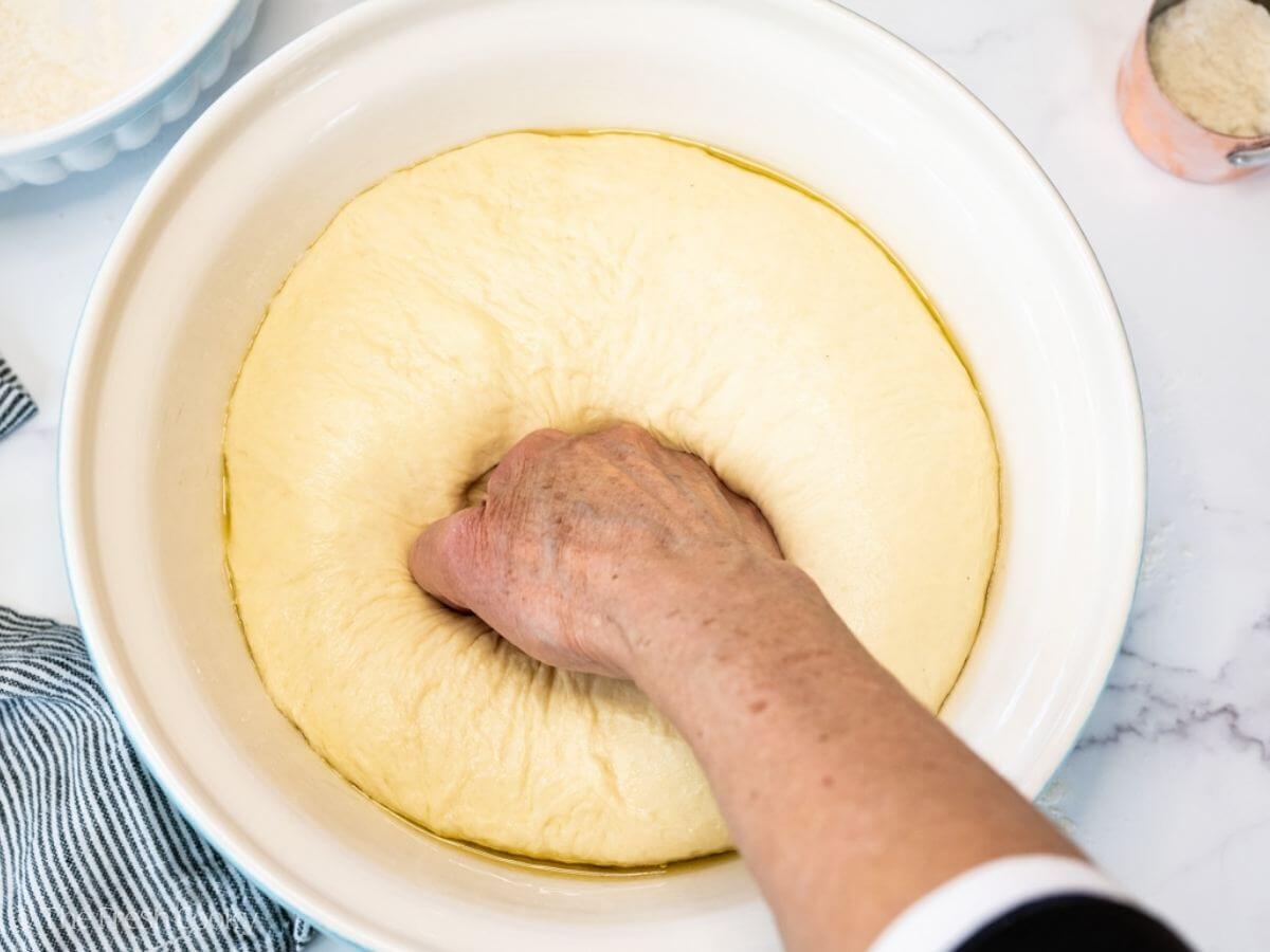 Punching the risen dough down in a large bowl.