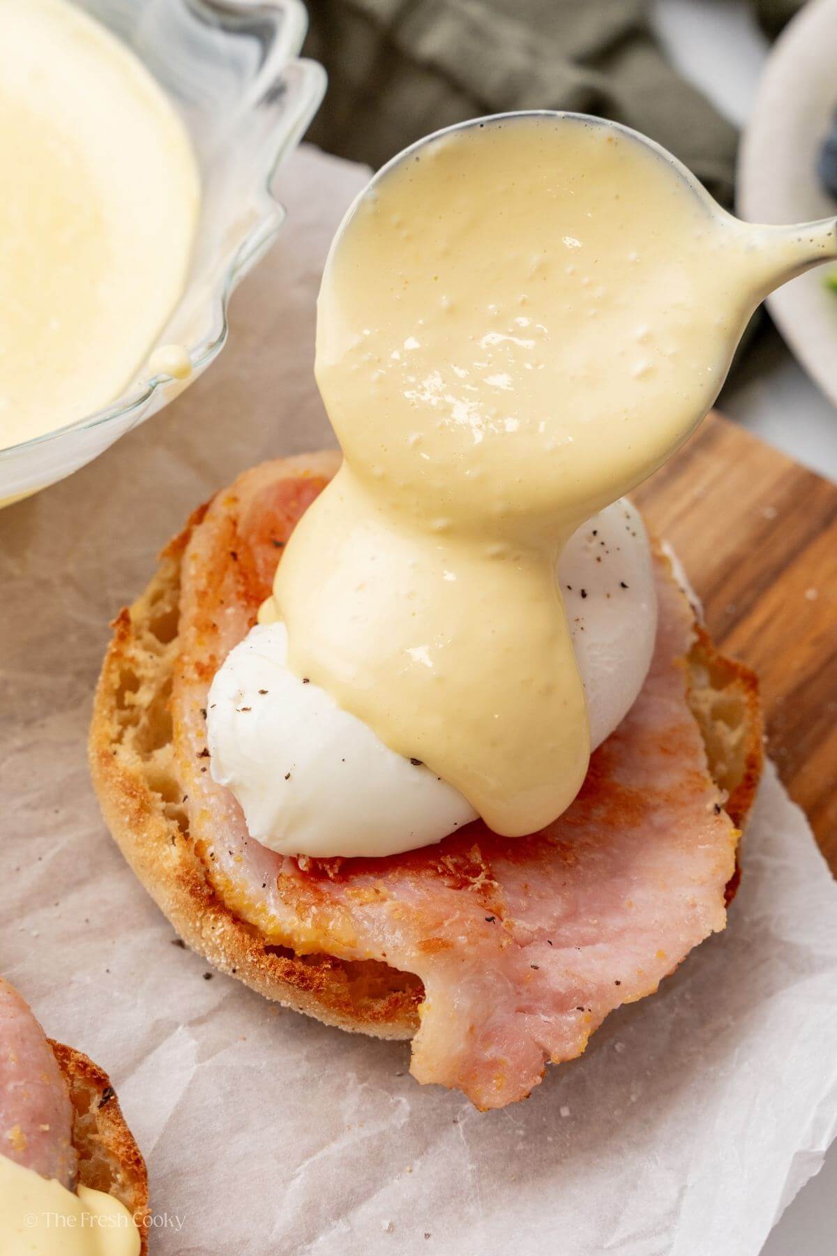 Pouring hollandaise sauce over eggs benedict.