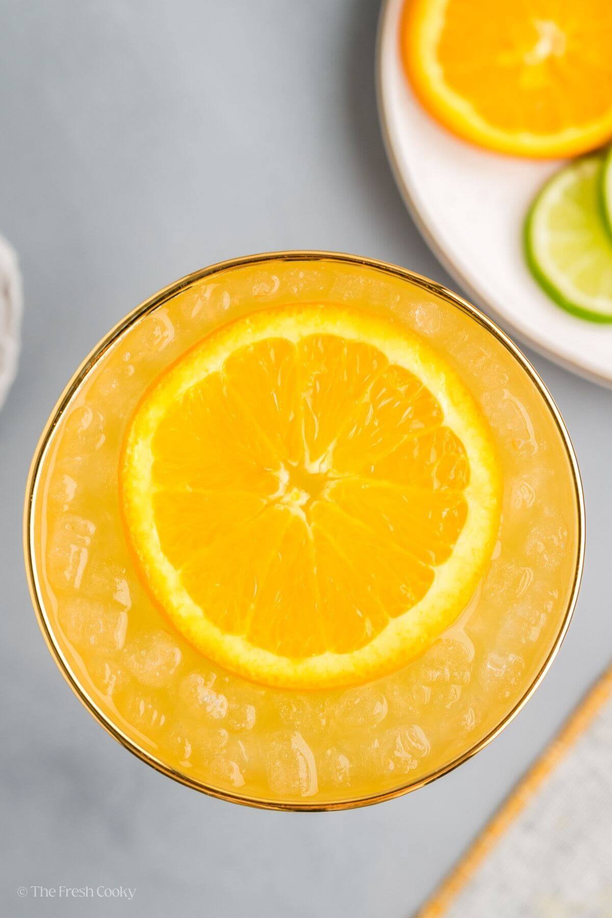 Overhead shot of a skinny margarita with an orange wheel on top.