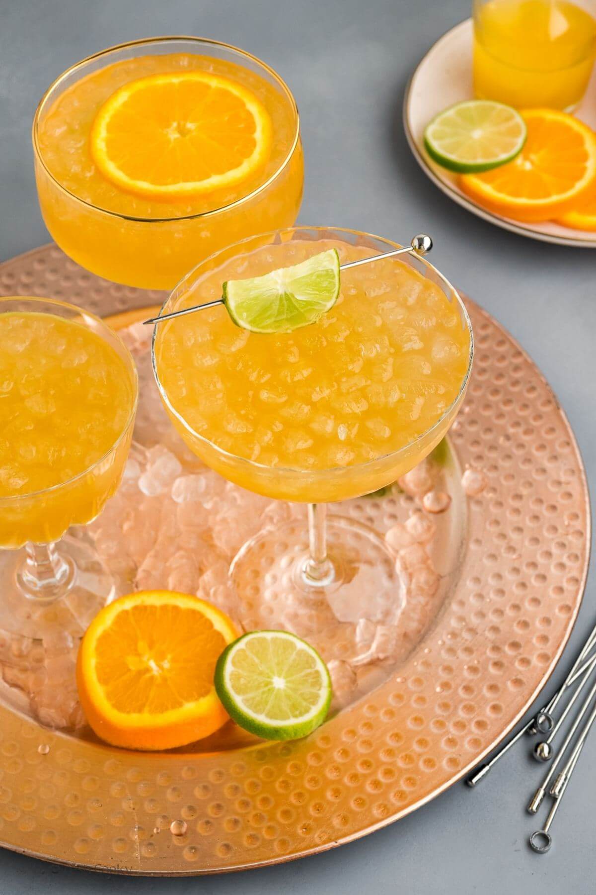 Three skinny margaritas on a serving platter with ice and citrus wheels.
