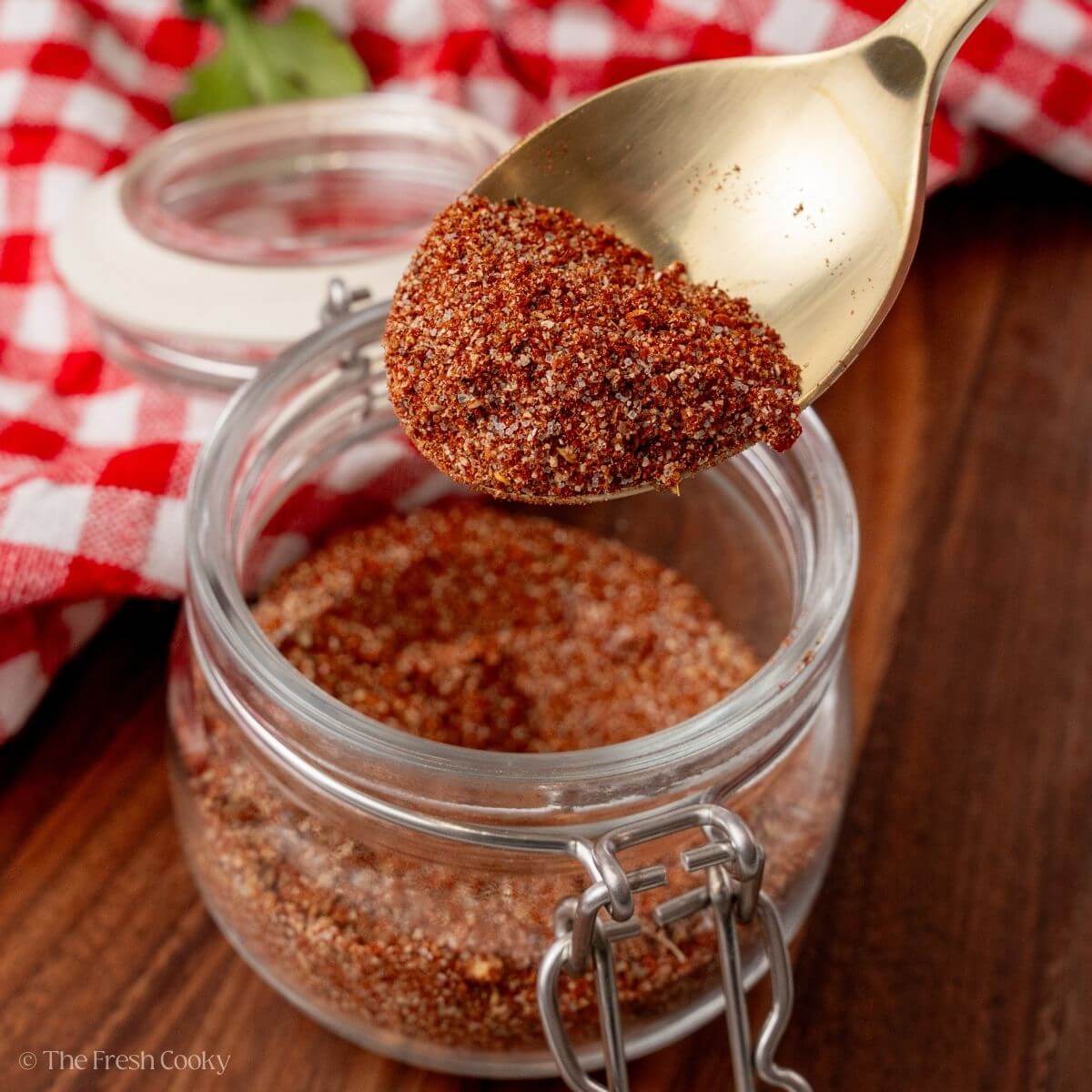 Spoon scooping up some of the homemade taco seasoning from a jar.