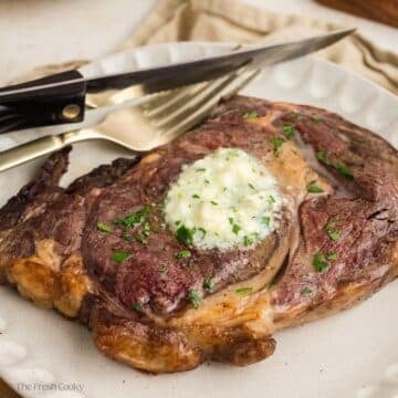 Juicy steak on a plate with a fork and knife.