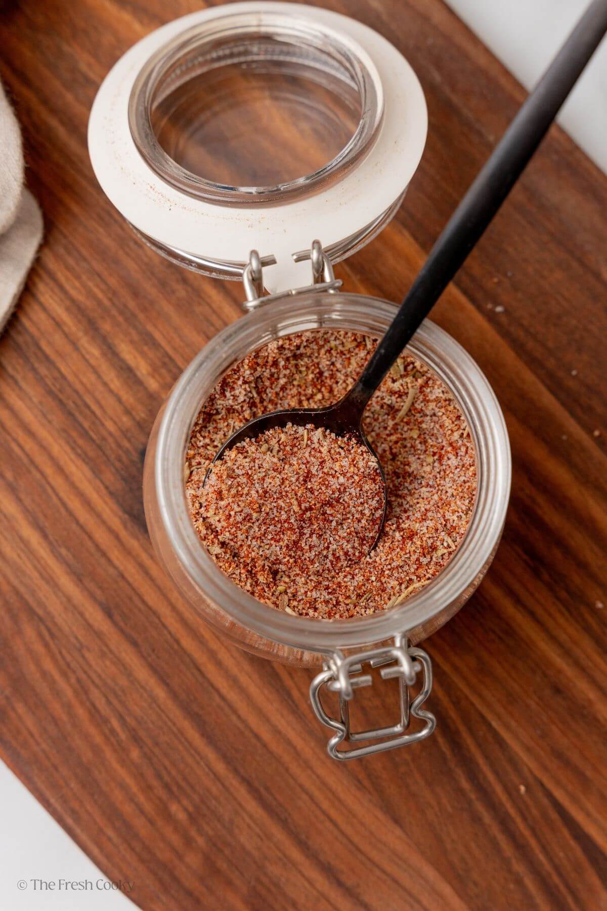Overhead shot of steak seasoning in a jar with a spoon in the jar.
