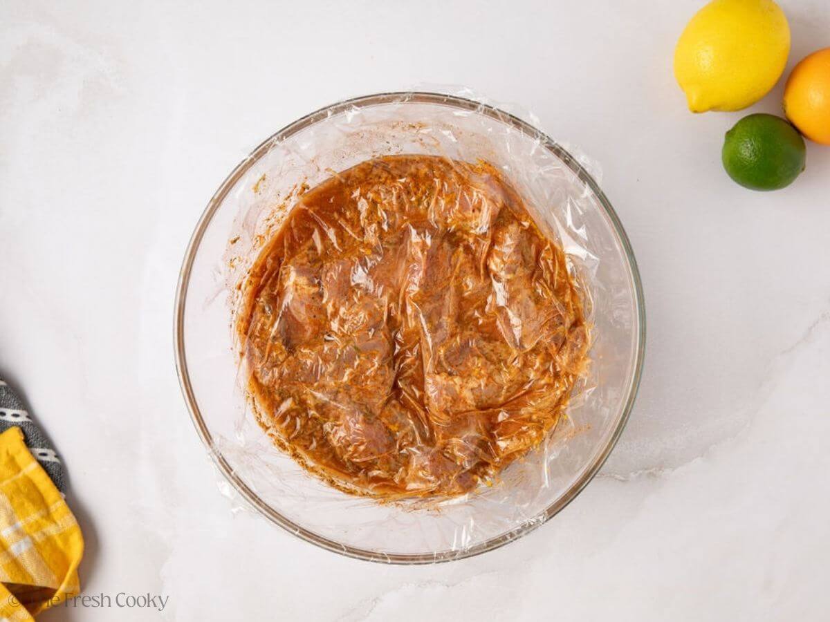 Pork added to the marinade with a piece of plastic on top.