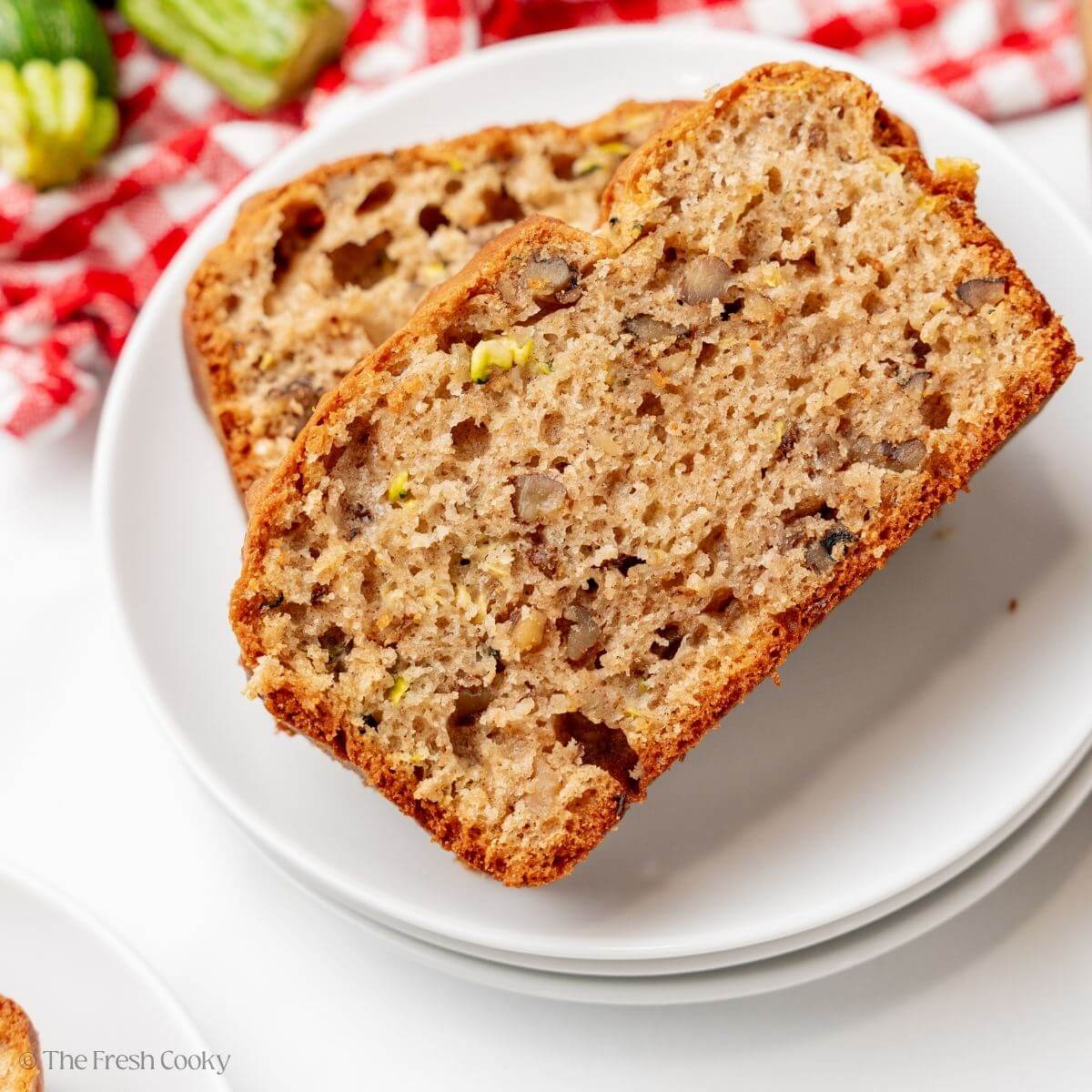 Two slices of zucchini bread on top of each other on a white plate.