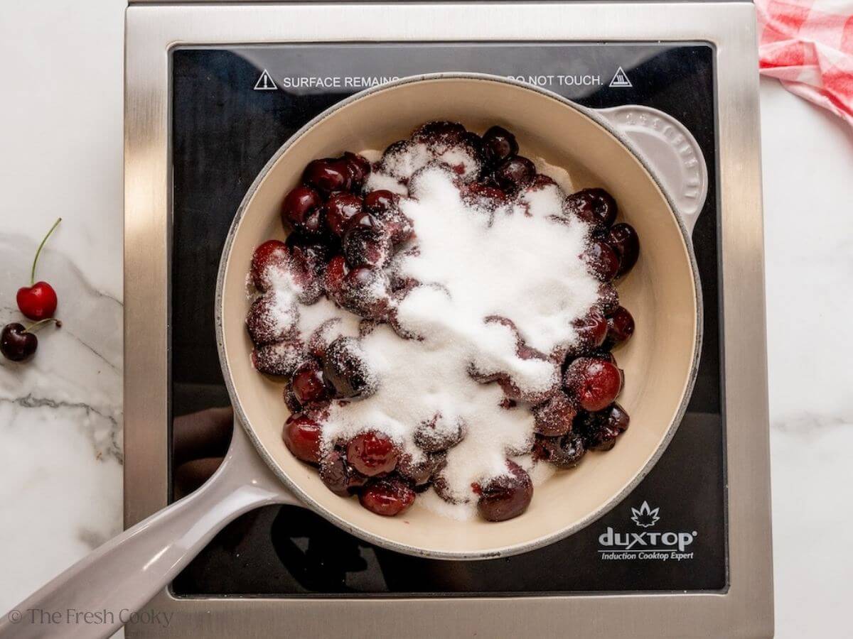 Sugar added to the cherry mixture in a skillet.