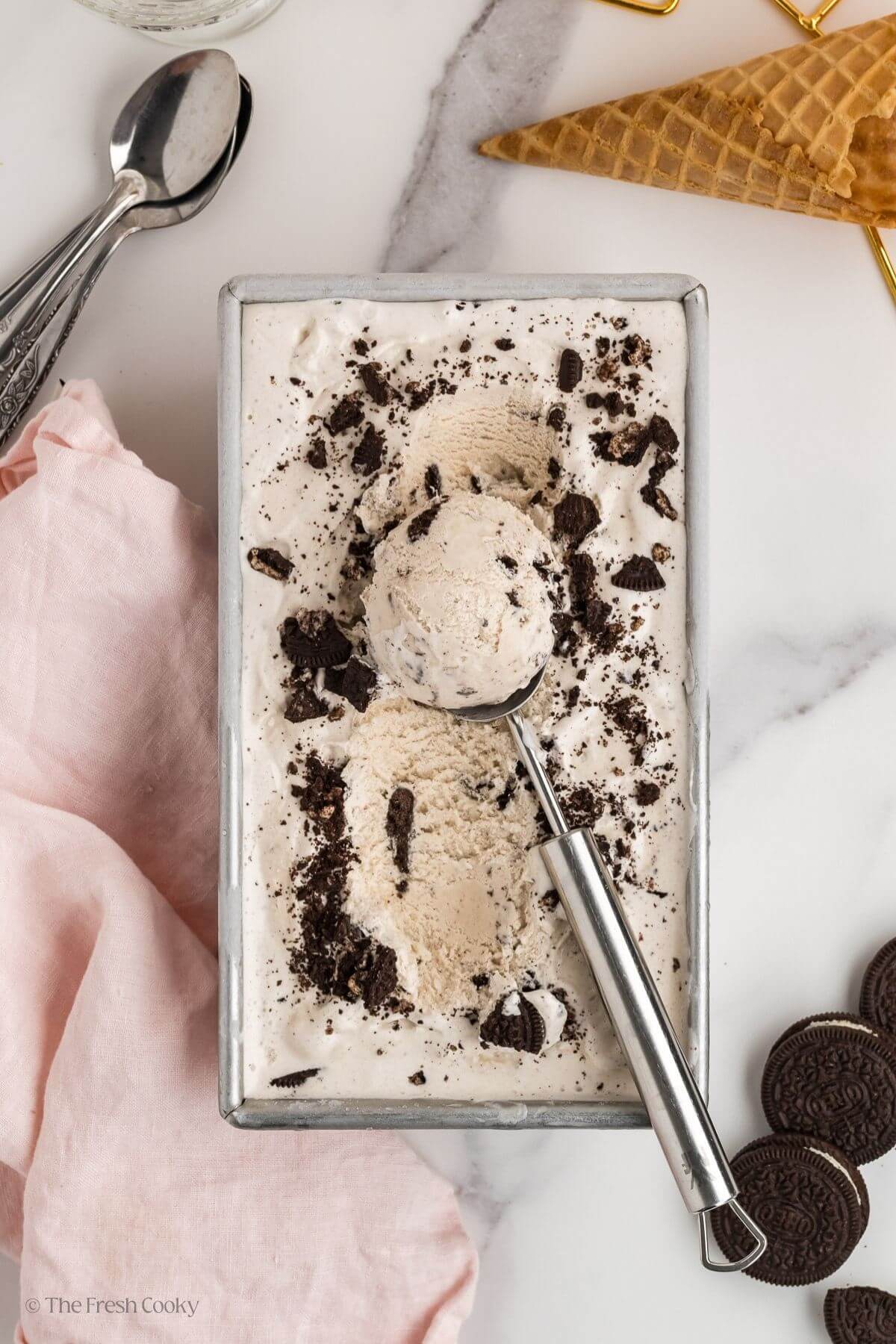 Overhead shot of cookies and cream ice cream with an ice cream scoop taking some.