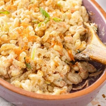 Sideview of Hawaiian macaroni salad in a clay bowl with a wooden spoon.