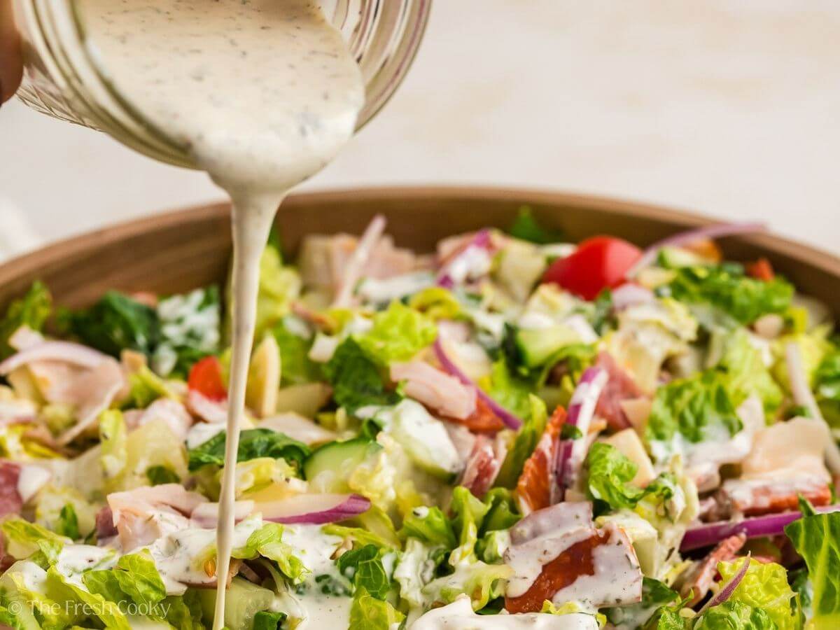 Pouring the dressing over the top of the Italian sub salad.
