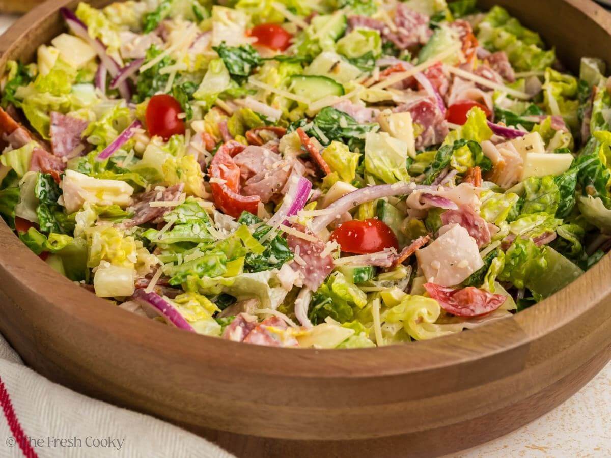 Grinder salad in a wooden salad bowl after being mixed with the dressing.