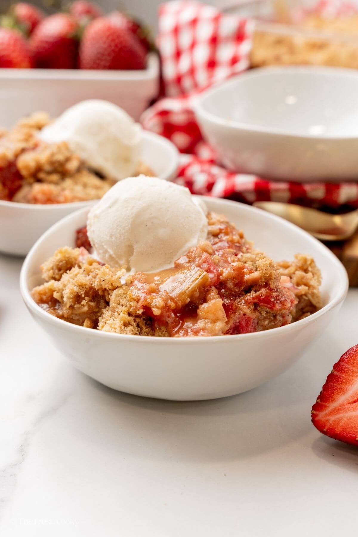 Side view of two bowls of rhubarb crisp with ice cream on top.
