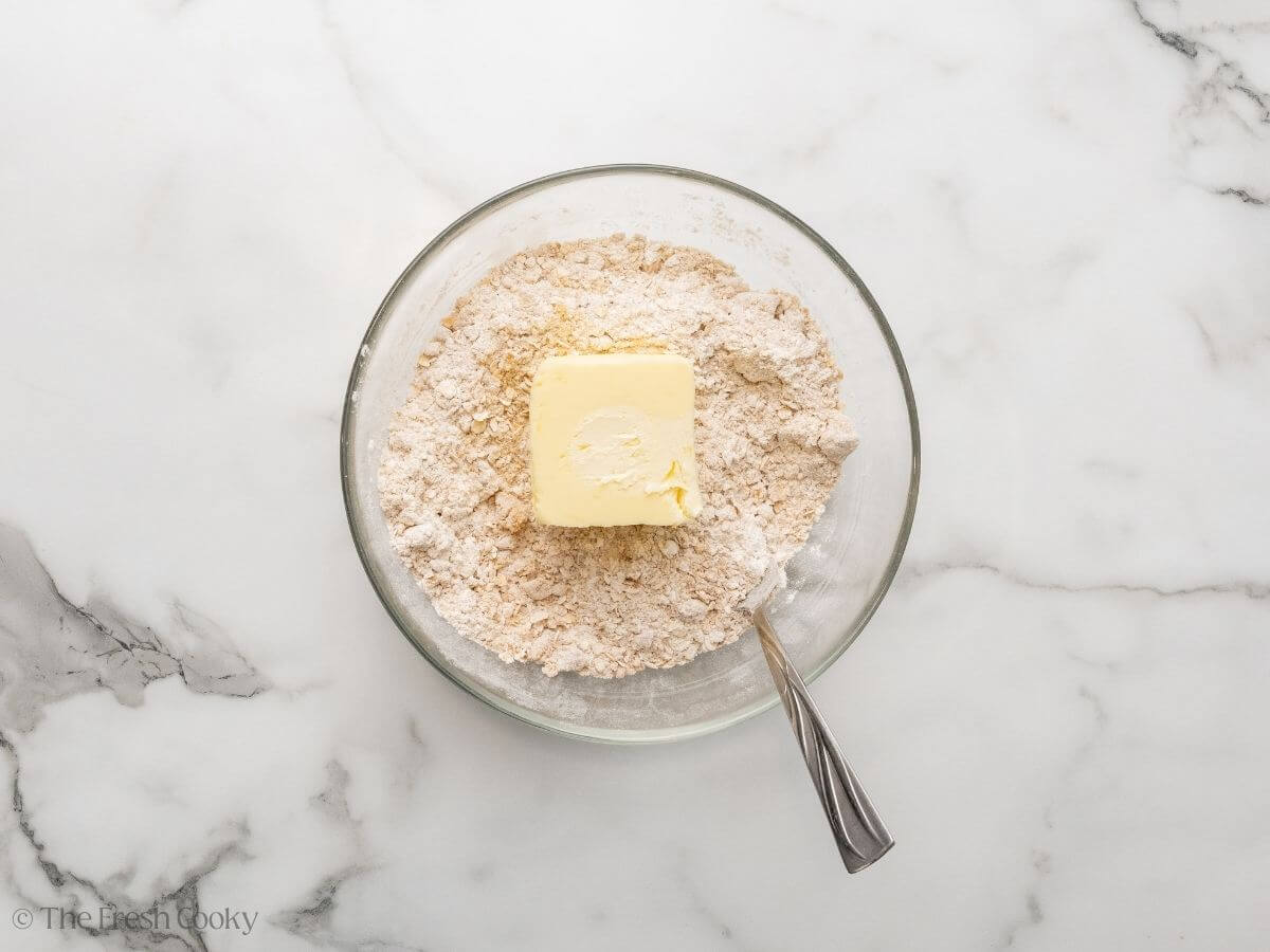 Butter added to the crisp ingredients in a bowl.