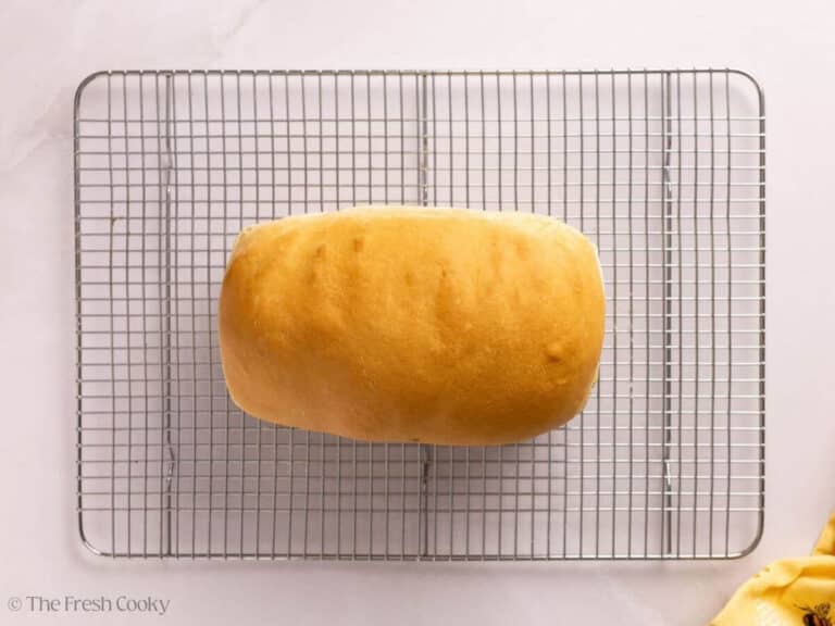Overhead shot of baked sandwich bread resting on a wire rack.