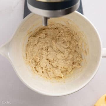 White sandwich dough in the beginning phases in a white mixing bowl of a stand mixer.