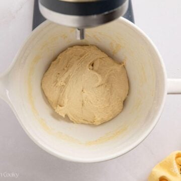 White sandwich dough after mixing in a white stand mixer bowl.
