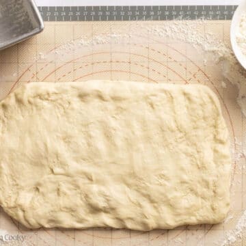 Bread dough rolled our into a rectangle on a floured surface.
