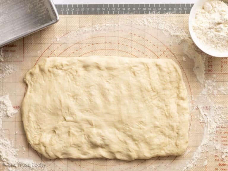 Bread dough rolled our into a rectangle on a floured surface.