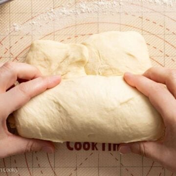 Two hands rolling up the bread dough.