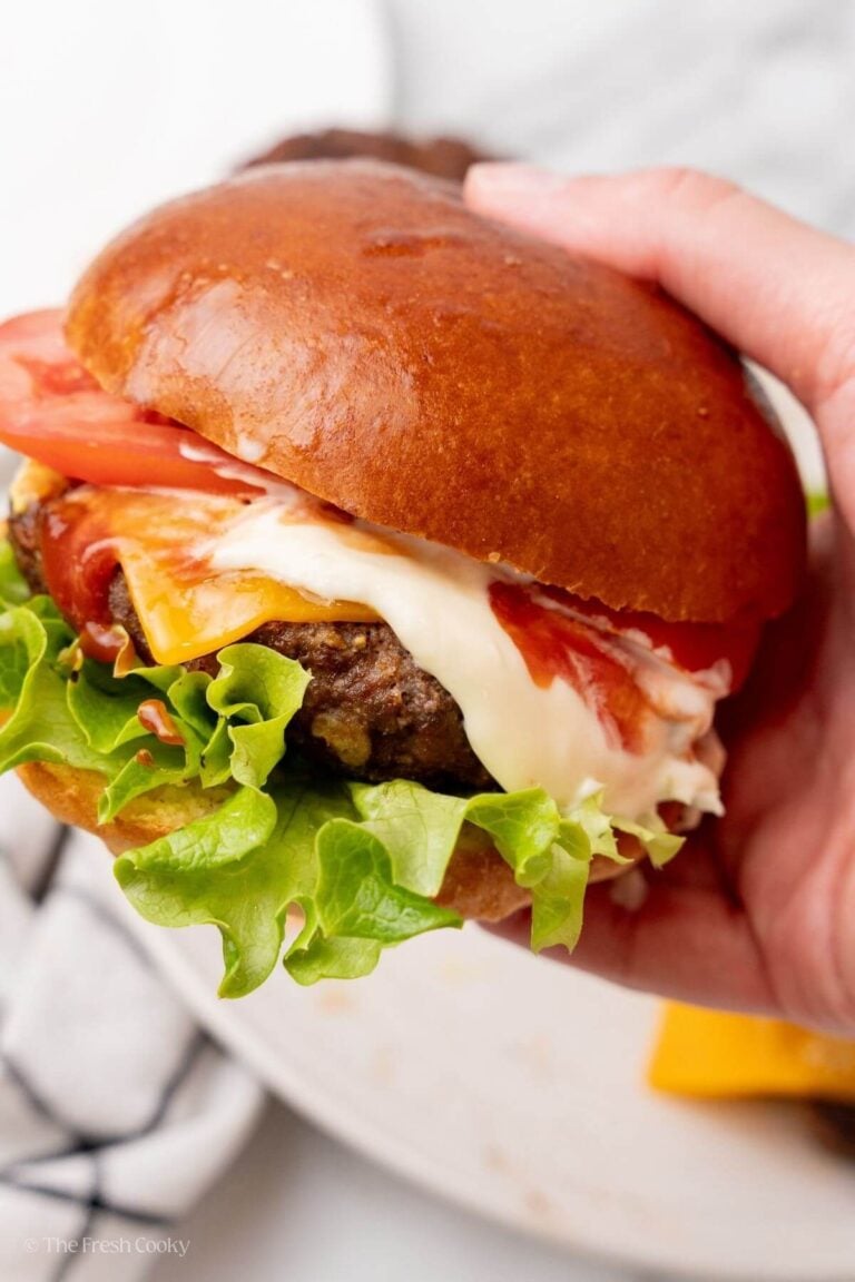 Hand holding a homemade burger with all the toppings.