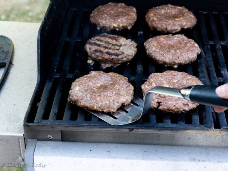 Flipping the hamburger patties on the grill.