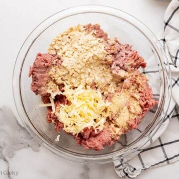 Additional ingredients added to the raw ground beef in a bowl.