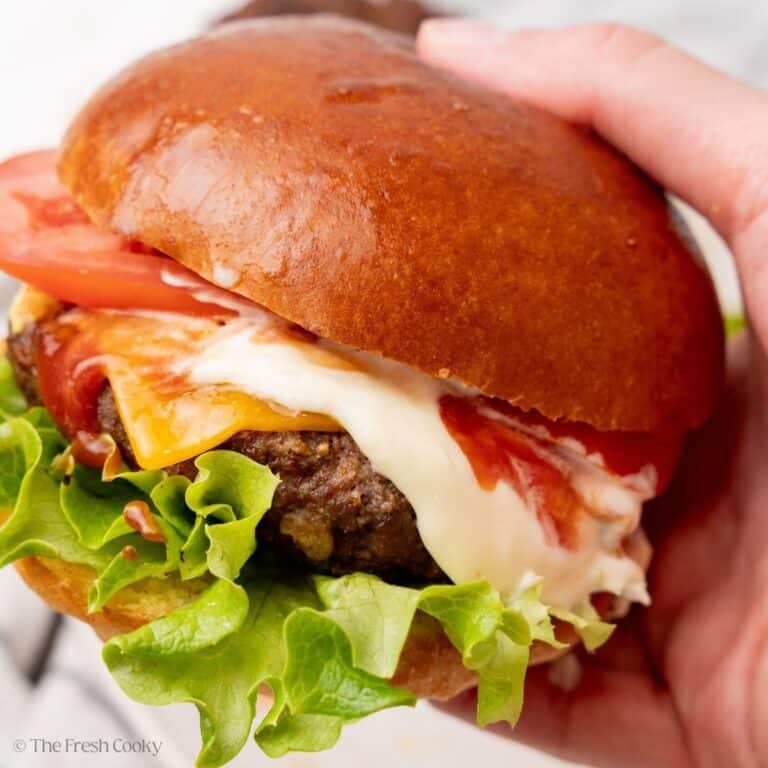 Hand holding a big, juicy, cheeseburger.