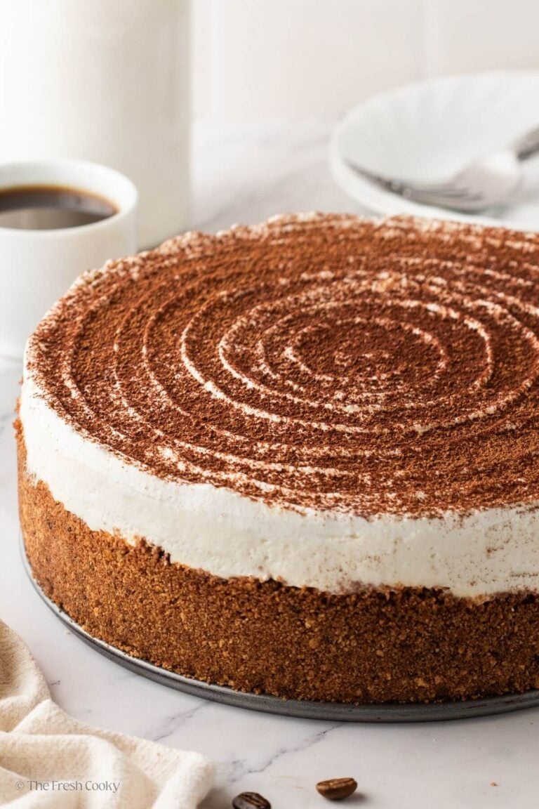 Tiramisu cheesecake on a platter with cocoa powder sprinkled on top.