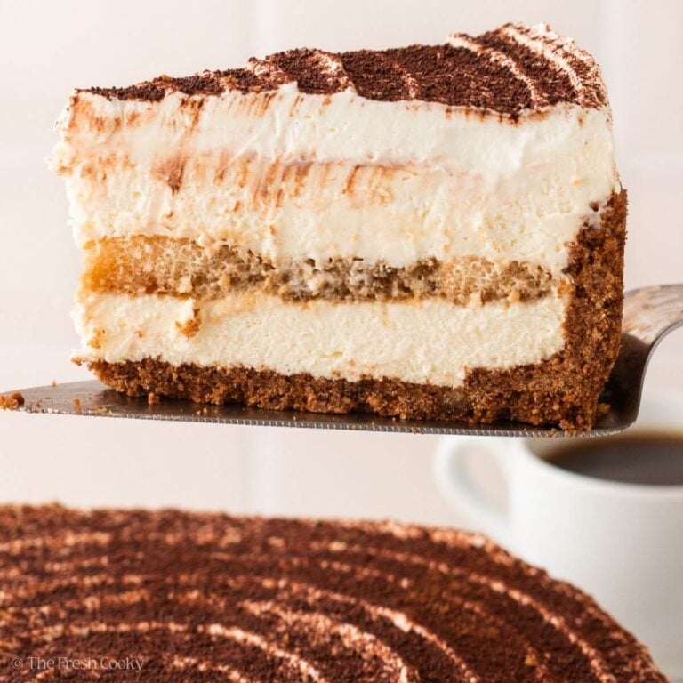 Side view of a slice of tiramisu cake on a metal spatula.