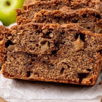 Slices of apple cinnamon bread leaning on each other on a wooden board.
