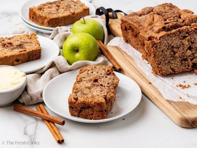 Slices of apple cinnamon bread on white plates next to the rest of the loaf.