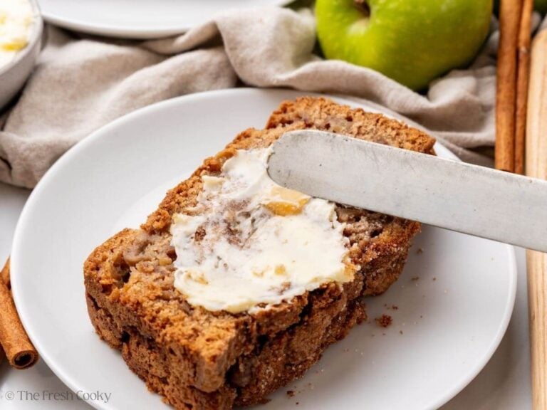 Spreading butter onto a slice of apple bread.