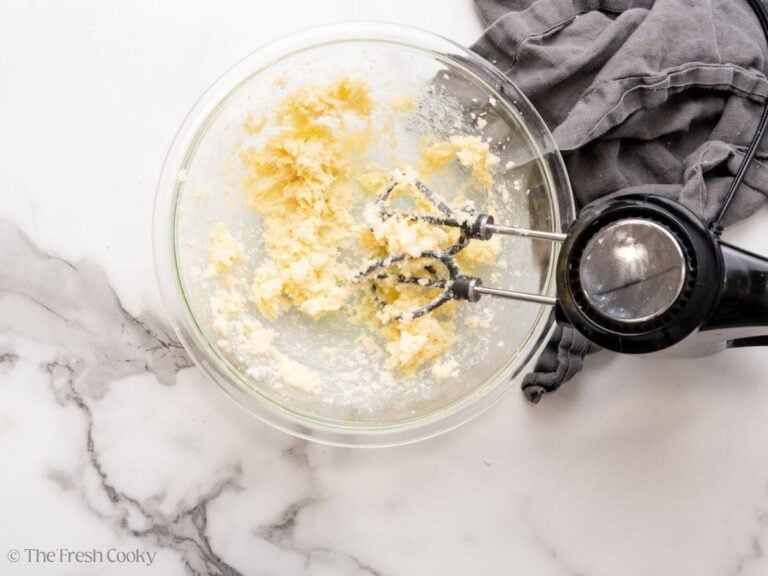 Using a hand mixer to cream the butter in a bowl.