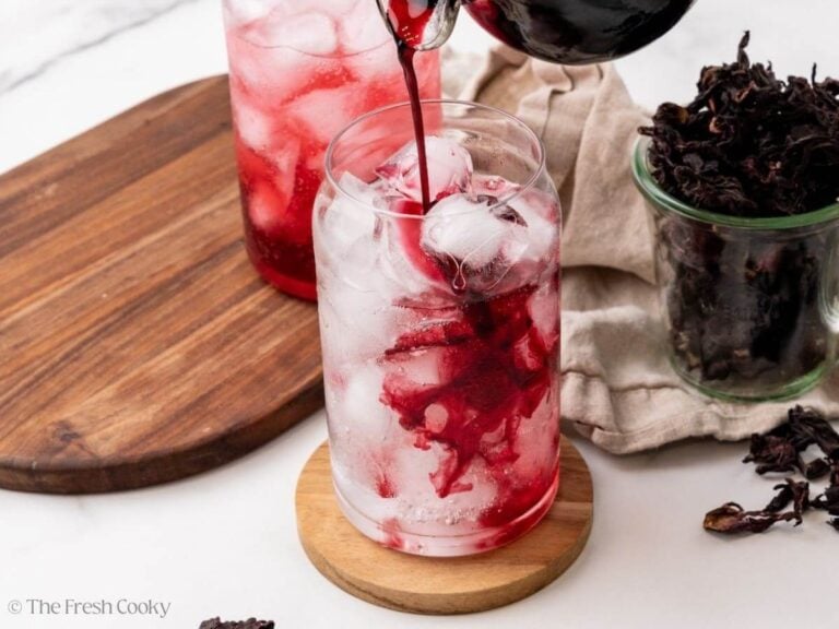 Pouring syrup into a glass of ice, to make a hibiscus mocktail.