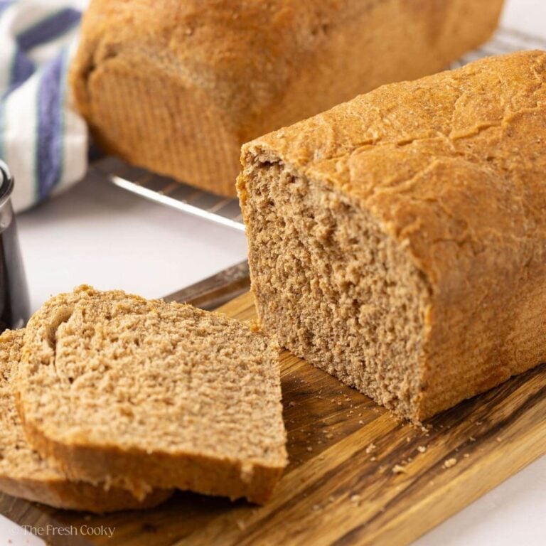 Whole what sandwich bread on a wooden board with two slices off the end.