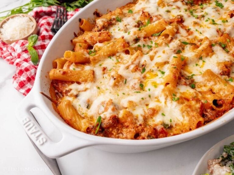 Cheesy baked rigatoni in a white oval baking dish.